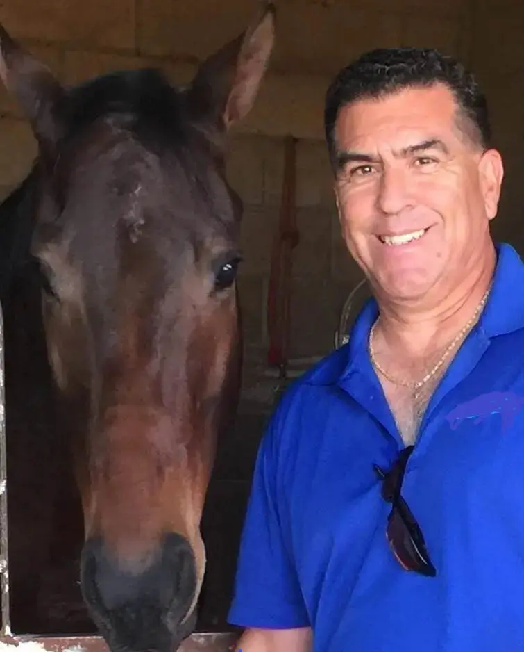 A man standing next to a horse in a stable.